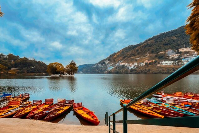 Colorful boats docked on a serene lake with hills in the backdrop during a Nainital trip