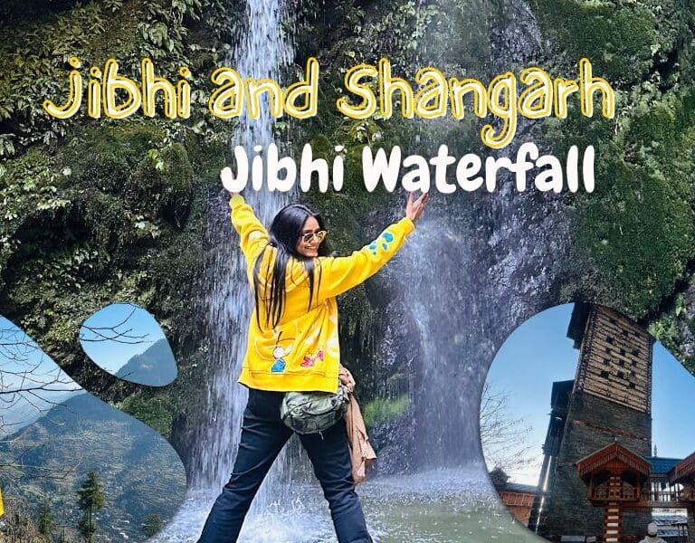 Woman in a yellow jacket facing a waterfall with arms raised at the jibhi waterfall spot